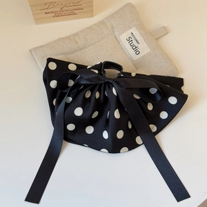 Détail de la pince à cheveux à pois avec rubans en satin sur fond de bois naturel