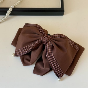 Detail of coffee brown bow hair clip with houndstooth ribbon edge and pearl accents