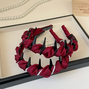 Detail view of handmade burgundy satin headbands with black spikes and pearls