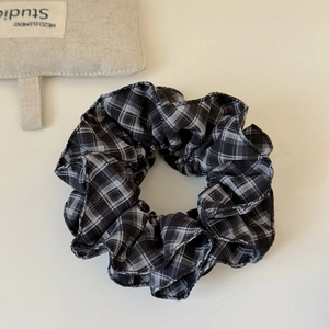 Detailed close-up of a black and white plaid scrunchie with high-quality fabric texture