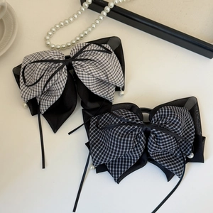 Detailed view of plaid bow hair clips with delicate black ribbons and pearl pendants