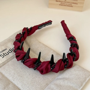 Macro shot of dark red pleated satin headband with black punk spikes and beaded chains