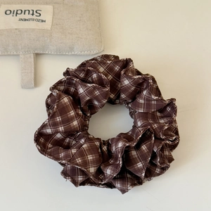 Detailed view of a brown plaid scrunchie with classic checkered fabric texture