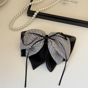 Detail of checkered bow hair clip featuring elegant long ribbons and pearl accents