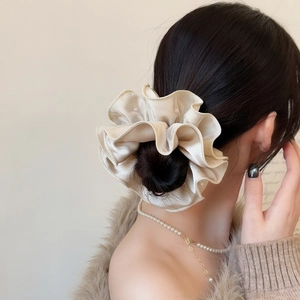 Detail von cremefarbenem Rüschen-Haargummi mit Perlenkante und Satin-Effekt im Haar
