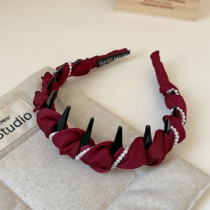 Detail of burgundy satin headband with pearls, spikes and Hand Made woven label