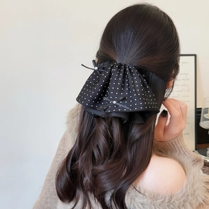Elegant black polka dot hair claw clip with pearl accents shown on model hair
