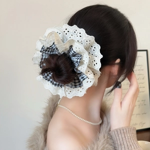 Detail of layered white lace and black check fabric scrunchie worn on a bun hairstyle