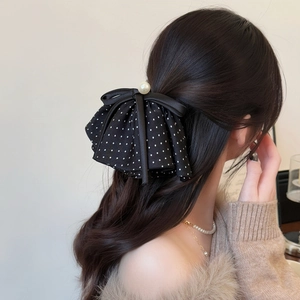 Close-up of a polka dot bow hair clip with a pearl center on a woman's hair