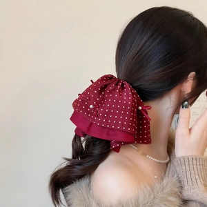 Elegant red polka dot bow hair clip with pearl detail shown on a woman back hairstyle