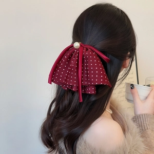 Polka dot bow hair clip with pearl center on brunette hair for elegant styling