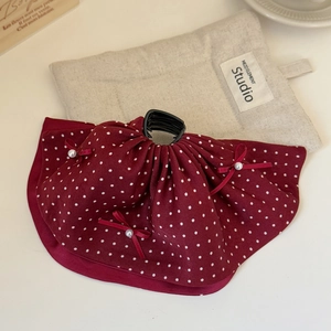 Close-up of wine red polka dot hair claw clip with bow and pearl on a rustic background