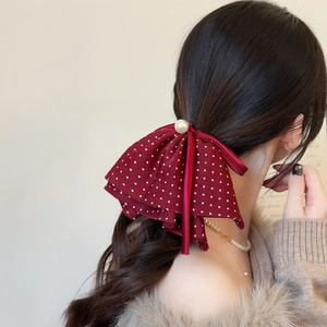 Detail of red polka dot ribbon hair clip with pearl center on low ponytail hairstyle