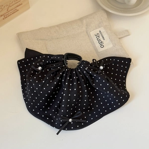Detailed close-up of a polka dot bow hair claw clip with pearls on beige linen fabric