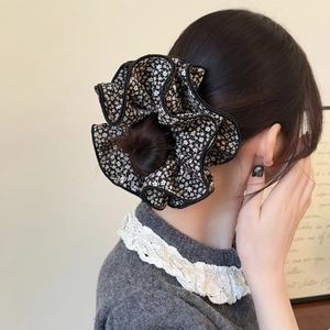 Close-up of a large floral scrunchie with black edging on a stylish high bun