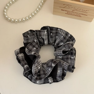 Detail of checkered scrunchie with bow patterns and black pleated edges in French style
