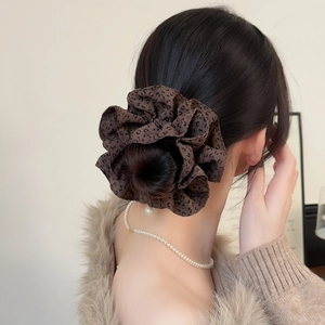 Chouchou élégant à motif léopard porté par un mannequin pour une coiffure chic