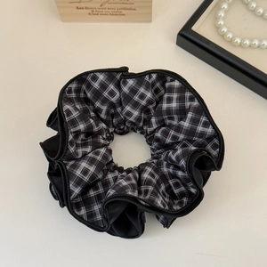 Detail of a large black and white checkered scrunchie with multi-layered pleated edges