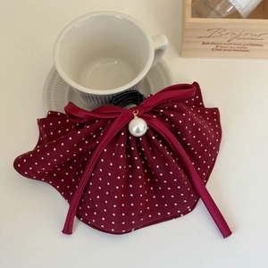 Detail of burgundy polka dot bow hair clip with a large pearl center and black plastic claw