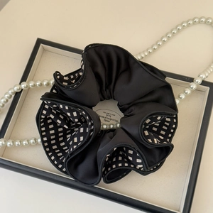 Detail of elegant black satin scrunchie with checkerboard pattern and pearls