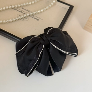 Detail view of a black French bow hair claw with elegant rhinestone trim and matte finish