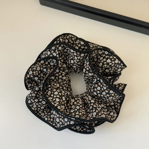 Detail of floral scrunchie with cream flowers on black fabric and layered ruffled edges