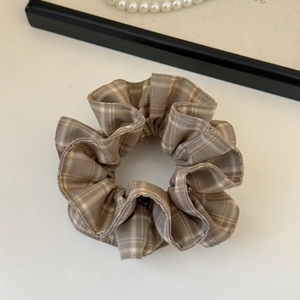 Détail du chouchou à carreaux marron café avec texture de tissu doux et plis élégants