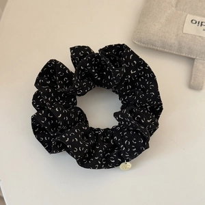 Détail du chouchou noir avec motifs blancs et petit pendentif en métal doré