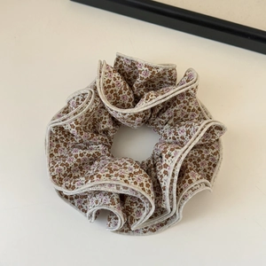 Detail of floral scrunchie with brown and pink patterns and beige stitched edges