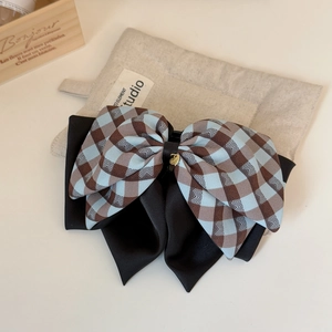 Close-up of blue plaid bow hair clip with black satin and golden heart pendant