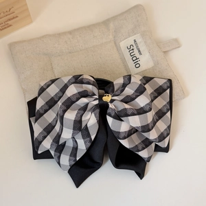 Detail of black and white plaid bow hair claw with gold heart-shaped metal accent