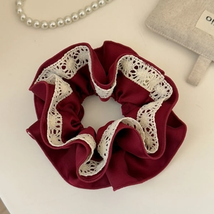 Dettaglio dell'elastico per capelli rosso scuro con elegante bordo in pizzo all'uncinetto