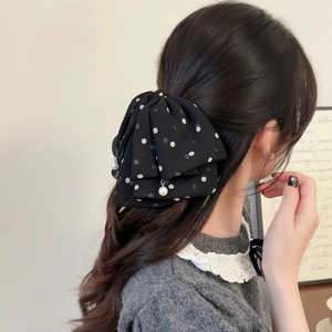 Detail of black polka dot mesh bow hair clip with elegant white pearl pendant decoration