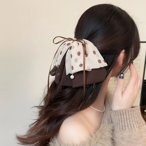 Polka dot mesh hair claw clip with bow and pearl pendant shown on hair back