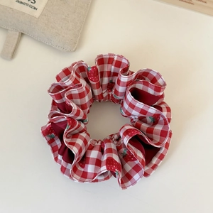 Detailed view of red plaid hair scrunchie featuring cute strawberry patterns and soft texture
