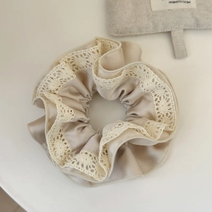 Dettaglio dell'elastico in raso champagne con bordo in pizzo bianco e trama plissettata