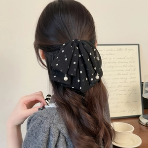 Elegant black polka dot mesh bow hair clip with pearl pendants on long wavy hair