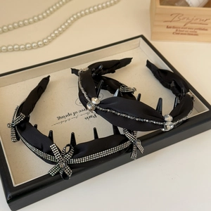 Close-up of black satin headbands featuring rhinestone bows and beaded crystal details