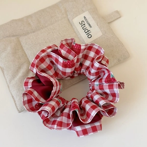 Red plaid double-layered scrunchie hair tie with ruffled design on beige background