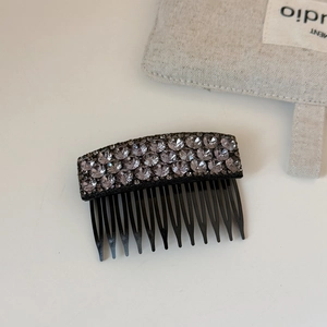Close-up of elegant black hair comb with three rows of shiny sparkling rhinestones