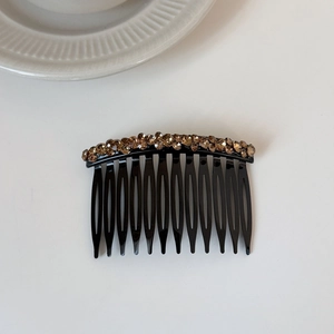 Close-up of elegant hair side comb with sparkling amber crystals and polished black teeth