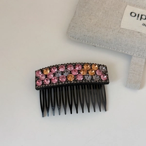 Detailed macro view of hair comb with sparkling pink and grey rhinestones and multi-tooth design