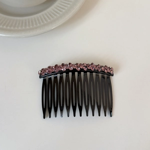 Detail of elegant black hair comb with glittering purple rhinestones for hair styling