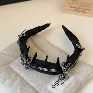 Detailed view of black satin headband featuring rhinestone bows and double row crystal trim