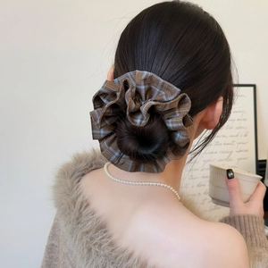 Close-up of a large oversized vintage plaid scrunchie styled on a classic bun hairstyle