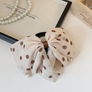 Detail of beige polka dot mesh hair claw clip with elegant hanging faux pearl charms