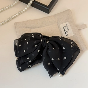 Close-up of black mesh polka dot bow hair clip with pearl charms and chiffon fabric