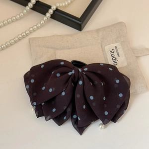 Detailed view of chiffon bow hair claw with blue dots and elegant pearl charms