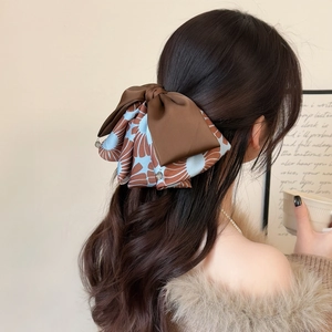 Elegant bow hair claw clip with vintage brown satin and patterned fabric on a model