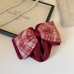 Detailed shot of a French plaid bow hair claw clip with dark red ribbon and pearl pendant